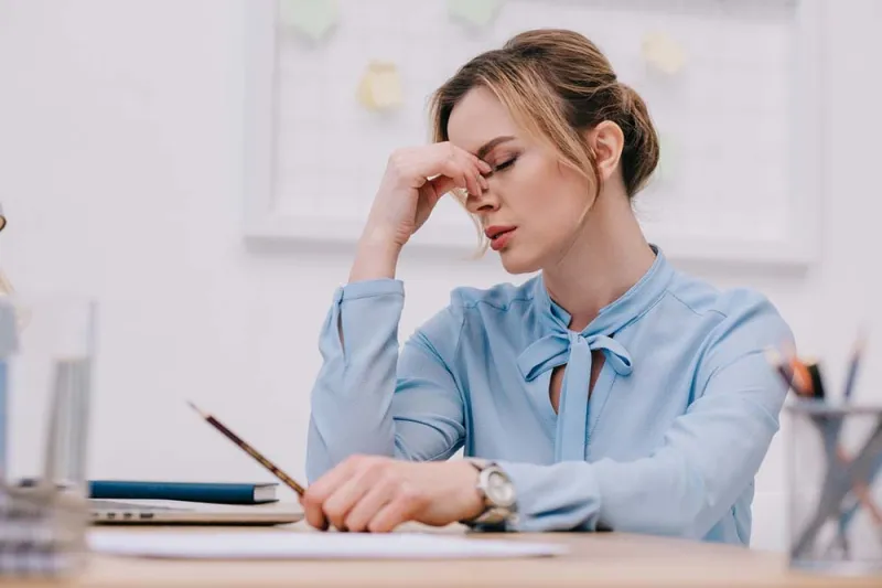 Woman feeling stressed and fatigued at her desk.